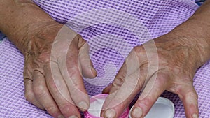 Old lady smears her hands with white cream. Senior women hand skincare