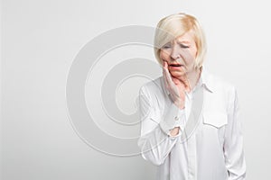 Old lady is suffering from a toothache. It started to ache suddenly. She needs to go to dentist. on white