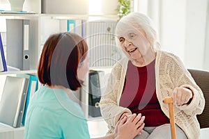 Old lady talking to caregiver holding hands