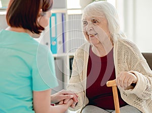 Old lady talking to caregiver holding hands