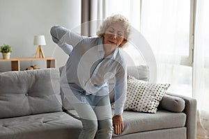 Old lady touching back feel ache getting up from sofa