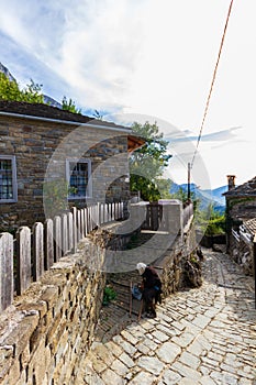 Old lady on a traditional stone-paved street, Mikro Papigko village, Epirus, Greece