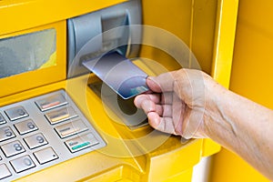 Old lady woman entering press button number code on machine to withdraw