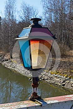 Old lamp on canal bridge handrail.