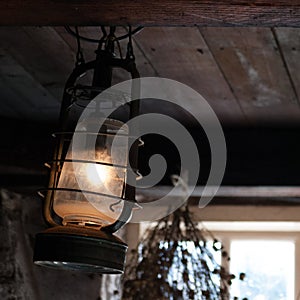 Old lamp hanging from wooden ceiling beam