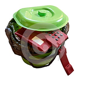 Old landline phone thrown into the trash bin. Isolated. White background