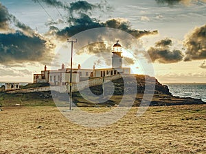 Old landscape lighthouse, white light tower with building for navigation on the thin spit of island