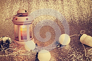 Old lantern with burning candle stands on silver background