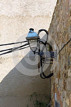Old lantern on the structural medieval wall and modern electrical cables.