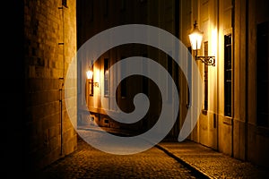 Old lanterns illuminating a dark alleyway medieval street at night in Prague, Czech Republic.