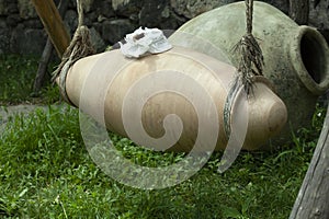 Old large jugs of wine, clay qvevri amphora lie on the grass,