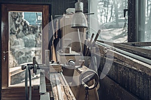 Old lathe in an old carpenter`s standing by a window covered with dust and spiderwebs