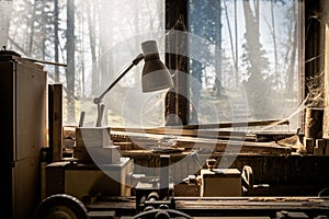 Old lathe in an old carpenter`s standing by a window covered with dust and spiderwebs