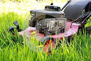 Old lawn mower in tall grass, neglected gardening