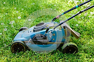 Old lawnmower on green grass in the park