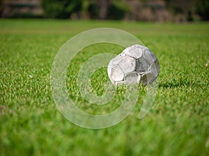 Old leak football/soccer ball abandoned on green grass field. Concept of sadness, hopeless and loneliness