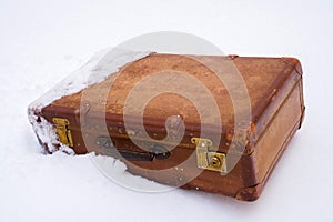 Old leather brown suitcase in the snow
