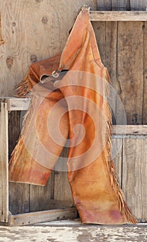 Old leather chaps on wood shelves.