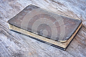 Old leather cover book on wood background.