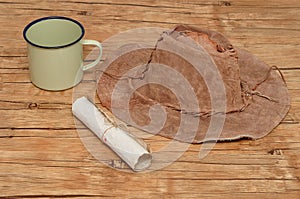An old leather hat with a paper scroll and tin mug