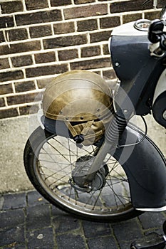 old leather helmet from the seventies on an old gray moped