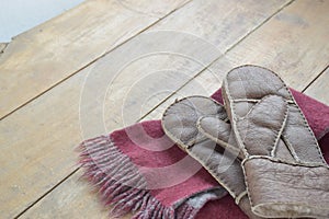 Old leather mittens and scarf on wood table