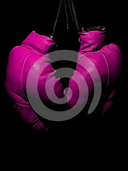 Old leather purple boxing gloves hanging in the dark
