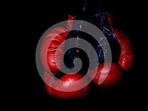 Old leather red boxing gloves hanging in the dark