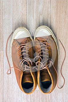 Old leather sneakers on wooden background top view, tonned vertical image.