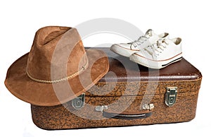 Old leather suitcase, retro sneakers, felt hat isolated on white background.