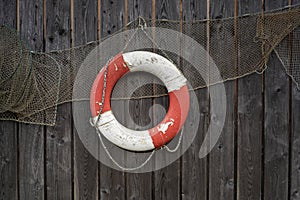 Old lifebelt and fishing net hanging on the wooden wall