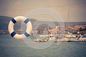 Old lifebelt hanging and fishing boats in the background