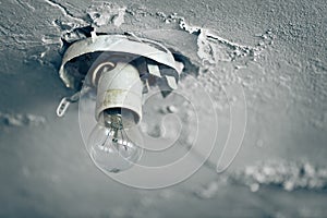 Old light bulb on ceiling of abandoned house