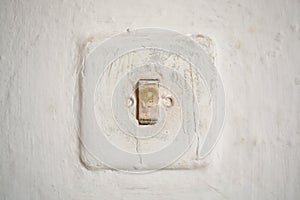 Old light switch on a white old wall on a traditional house in Romania