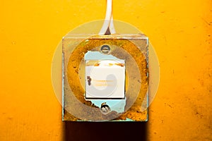 Old light switch on a yellow painted wall