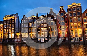 Old lighted houses bulidings at lighted sunset river channel in Amsterdam city