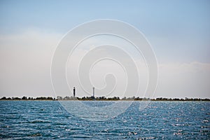 Old lighthouse on the beach near the sea. Lighthouse on the coast of the island Dzharylgach