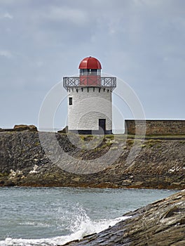 The Old Lighthouse at Burry Port with small waves breaking on the stone Shoreline. photo