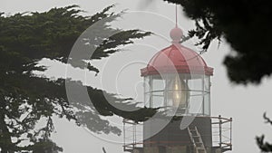 Old lighthouse fresnel lens glowing, foggy rainy weather. Illuminated beacon USA