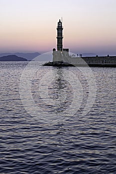 Old lighthouse in a quiet Harbor at sunset.