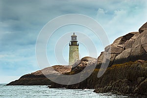 Old Lighthouse Tower on Rocky Maine Island as Sun Breaks Through Storm Clouds