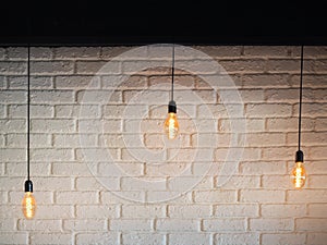 Old lighting electric bulb, Retro lamp on a background of a white brick wall. Edison bulb hanging on a wire. Three bulbs on a wire