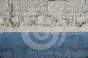 Old limewashed white wall with blue skirting board