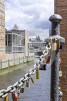 On an old link chain of the Speicherstadt in Hamburg hang many colorful so-called love locks in different shapes. The