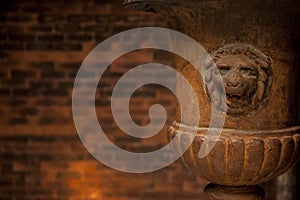 Old lion flower vase in front of a brick wall