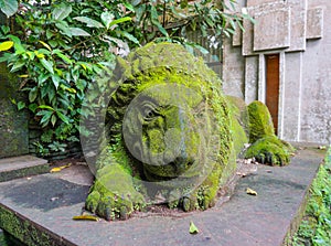 Old lion sculpture covered of green moss in Ubud monkey forest, Bali, Indonesia