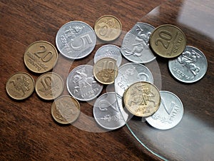 Old Lithuanian metallic money under the magnifying glass on wooden table, selective focus. Local currencies