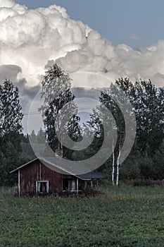 Old little house in Finland under amazing clouds