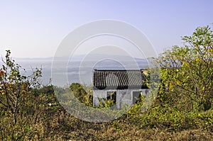 An old little hut on a mountain in the village of Luxiang in China. Behind the house you can see the sea and the horizon