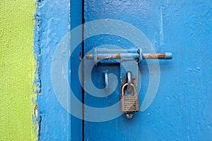 Old lock on the door but the door is opened. Green and blue wall.